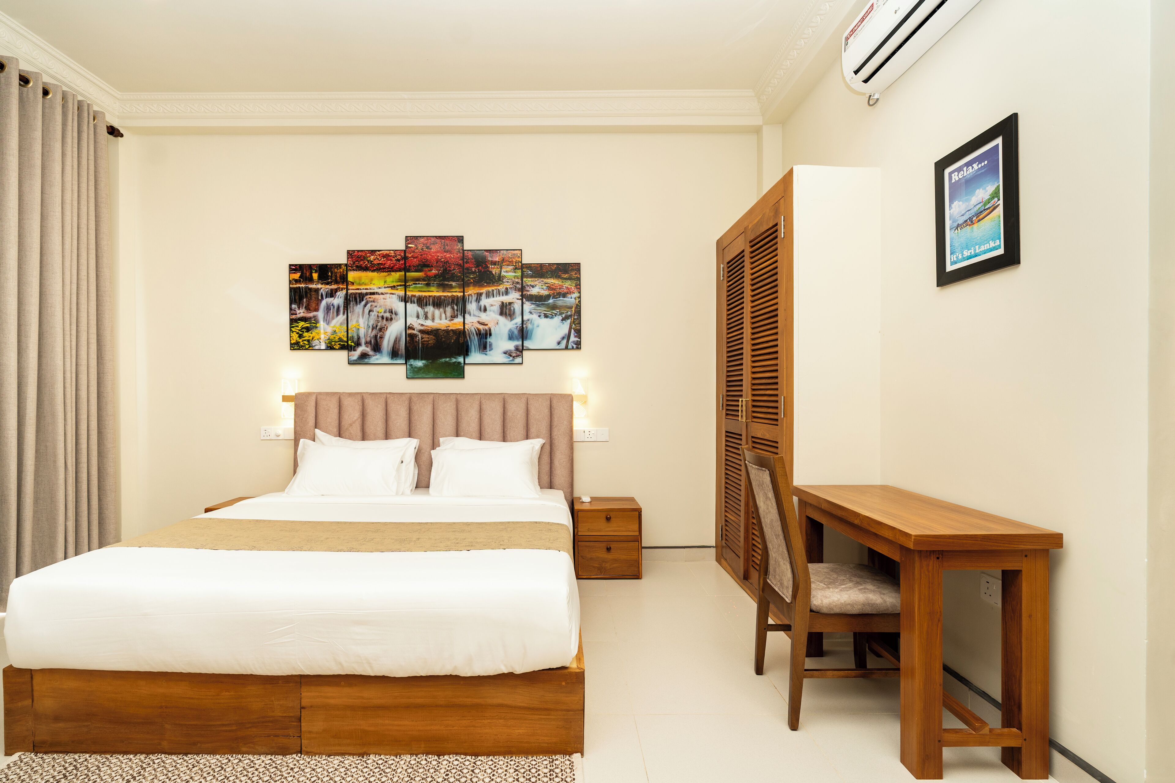 Una habitación de hotel con una cama grande, un escritorio y una obra de arte colgada en la pared.