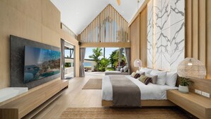Ein modernes Schlafzimmer mit großem Fernseher, einem Bett mit weißer Bettwäsche und Blick ins Freie.