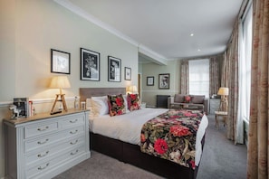 A hotel room with a bed, a desk, a chair, a lamp, and framed pictures on the wall. - THE White Horse Hotel Brasserie (Romsey)