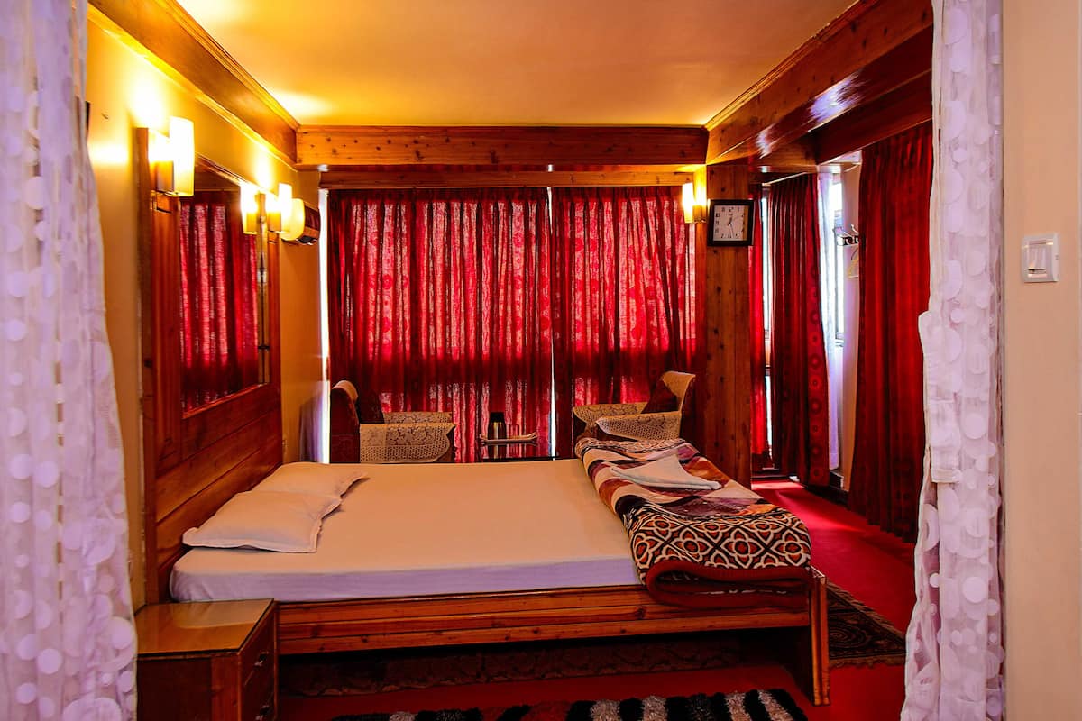 A room with a bed, a wooden headboard, a bedside table, and a red carpet.