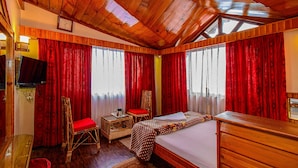 Ein Zimmer mit Holzwänden, einem Bett, einem Sessel, einem kleinen Tisch mit Tasse und einem Fernseher.