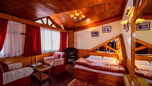 Ein gemütliches Holzhaus mit Schlafkoje, einer Couch und einem Kamin.