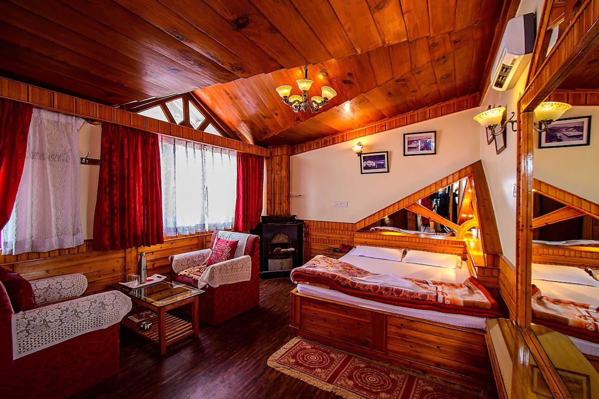 A cozy wooden cabin with a loft bed, a sofa, and a fireplace.