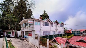 Ein zweistöckiges Hotel mit Balkon im oberen Geschoss, einem verschlossenen Eingang und einem roten Ziegeldach.