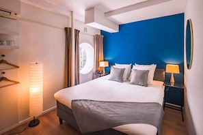 Habitación de hotel con una cama grande, lámparas de noche, una lámpara de pie y vistas por la ventana.