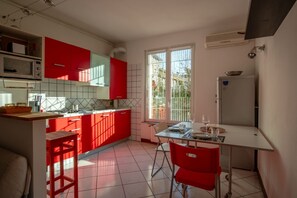 Une cuisine avec des meubles de rangement rouges, une table à manger et une fenêtre.