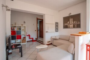 Un salon avec un canapé, une petite table, une bibliothèque et un téléviseur.