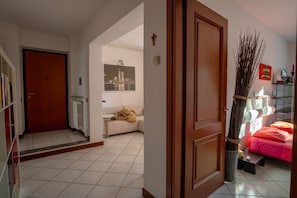 Ein Hotelzimmer mit Bett, Nachttisch, Fenster mit Blick, Tür und Flur zu einem weiteren Zimmer.