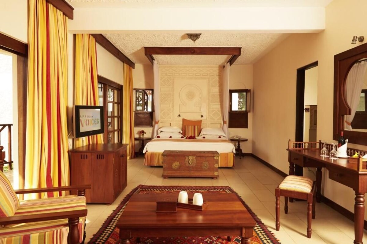 A bedroom with a bed, wooden furniture, a television, and a patterned rug.