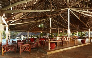 An open-air pavilion with wooden furniture and potted plants. - Neptune Village Beach Resort & Spa (Diani Beach)