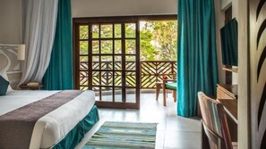 A bedroom with a bed, a nightstand, a chair, a TV, and a view of the outdoors. - Neptune Village Beach Resort & Spa (Diani Beach)