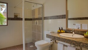 A modern bathroom with a glass-enclosed shower, a white toilet, a sink with a granite countertop, and a mirror above the sink. - Neptune Village Beach Resort & Spa (Diani Beach)