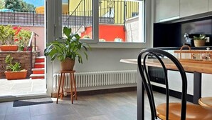Eine moderne Küche mit großem Fenster, einem Essbereich mit Holztisch und -stühlen sowie einem Blumentopf.