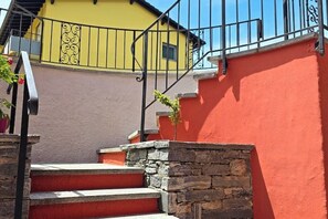 A staircase with stone steps leading to a balcony with a yellow wall and black railing. - Losone Ca.Dal Bagatt apartment (Losone)