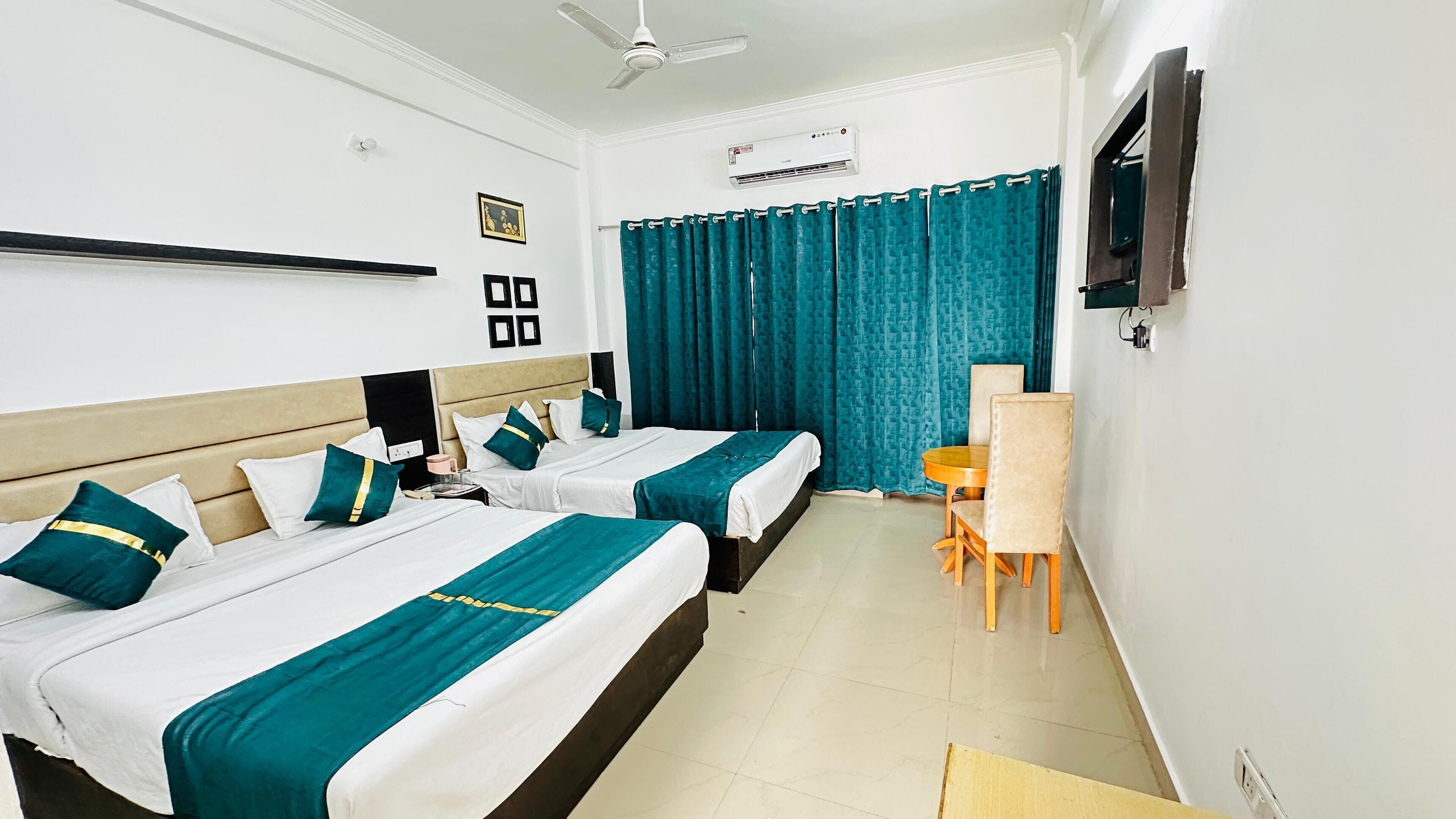 A hotel room with two beds, a desk, a chair, a TV, and a ceiling fan.