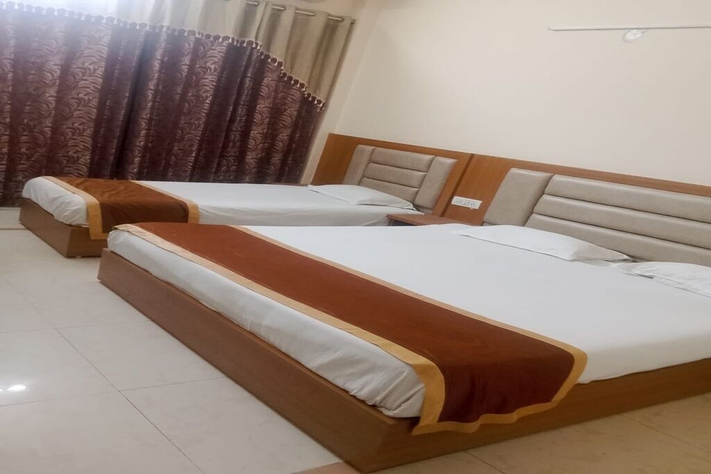 A hotel room with two beds, each with a wooden headboard and white bedding.