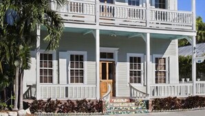 A two-story house with a balcony on the second floor, a front porch, and a staircase leading to the entrance. - The Southernmost Inn - Adult Exclusive (Key West)