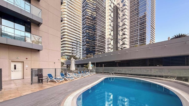 Una piscina sul tetto con lettini da relax e vista sui grattacieli.