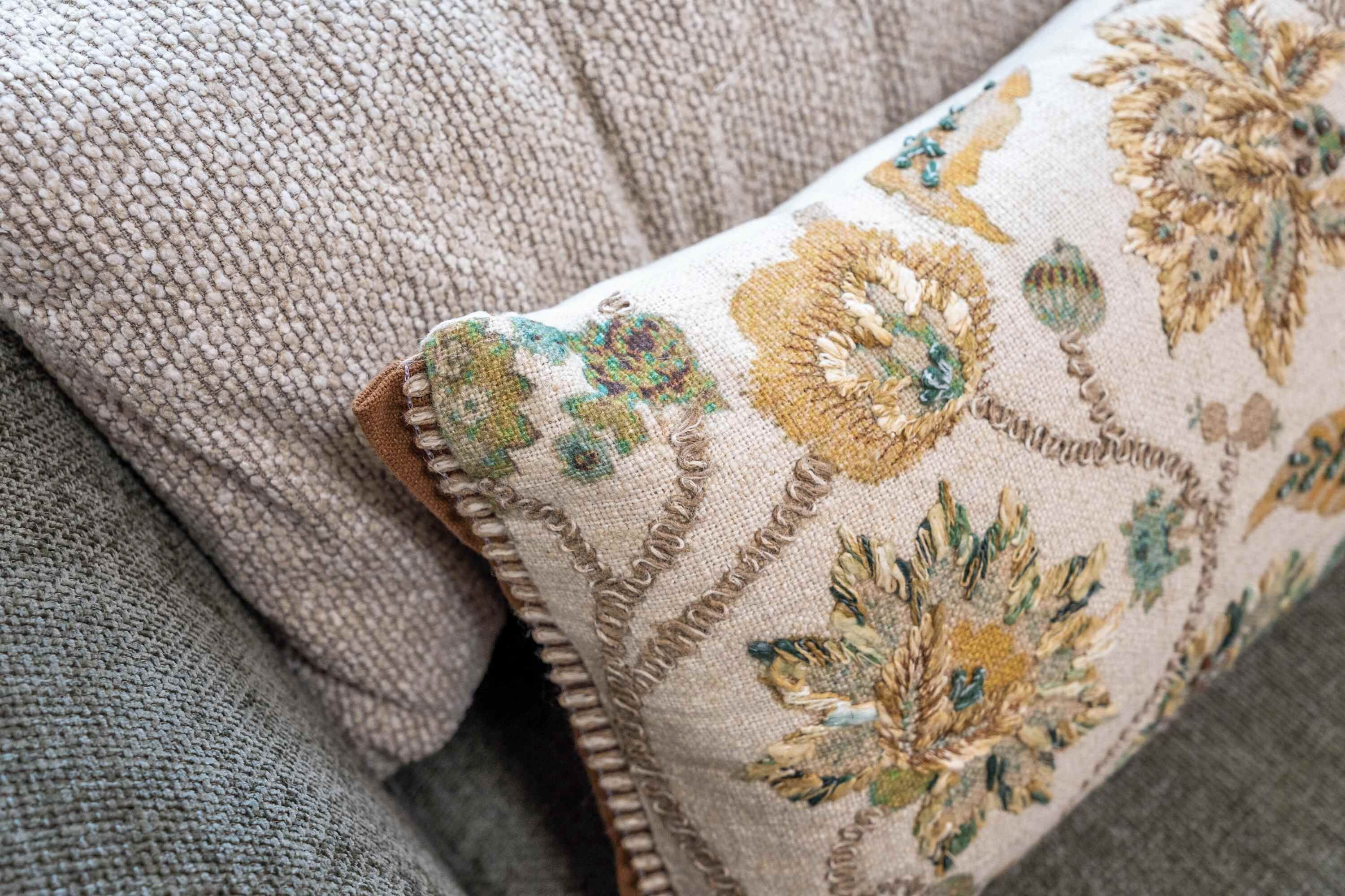 Primer plano de una superficie de tela texturizada con un cojín decorativo bordado con motivos florales.