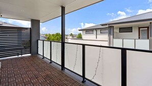 A balcony with a view of neighboring buildings and a clear sky. - Family-Friendly 4-Bed Home with Courtyard (Holt)