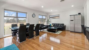A spacious living area with a dining table, black leather sofas, and a modern refrigerator. - Family-Friendly 4-Bed Home with Courtyard (Holt)