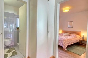 Quarto com cama, mesa de cabeceira e criado-mudo.