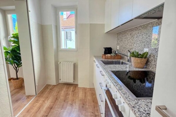 Uma cozinha moderna com bancadas de granito, uma pia dupla e forno embutido.