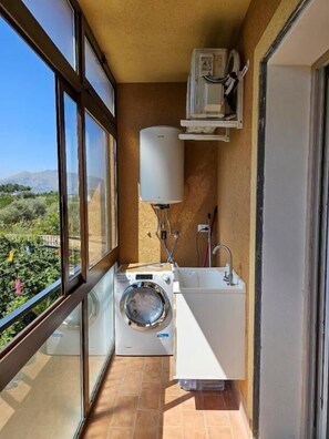 A compact balcony with a washing machine, a sink, and a water heater. - Aphrodite's apartment at Aspra (BAGHERIA)