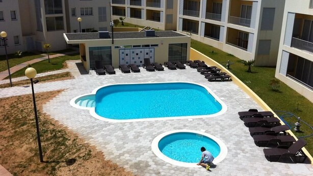 A swimming pool with lounge chairs, a small circular pool, and a building with balconies. - Paraiso Dourado (Porto Santo)