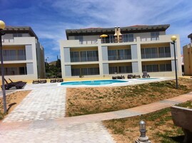 Un hotel moderno con piscina, zona de estar exterior y jardines.