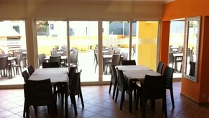 Un espace repas avec des tables et des chaises, de grandes fenêtres et une vue sur l’extérieur.