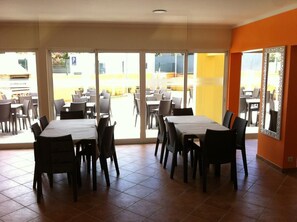 A dining area with tables and chairs, large windows, and a view of the outside. - Paraiso Dourado (Porto Santo)