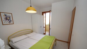 Une chambre à coucher comprenant un lit, une table de chevet, une armoire, une porte et un luminaire suspendu.