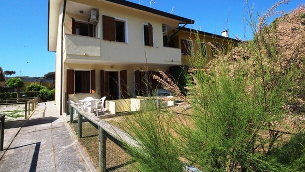 Un bâtiment à deux étages doté d’un balcon à l’étage supérieur, d’une allée pavée et d’un jardin agrémenté d’arbustes.