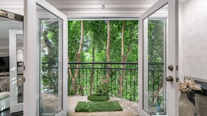 Un intérieur moderne avec une porte vitrée donnant sur un balcon qui offre une vue sur une forêt dense.