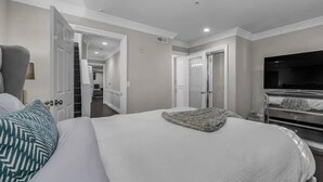Une chambre à coucher avec un grand lit, une télévision et un dressing.