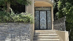 Un mur de pierre avec une porte en métal et des marches menant à un bâtiment.