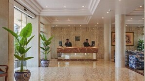 A spacious lobby with a marble floor, a reception desk, and two large potted plants. - Regent Hotel Andheri (Mumbai)