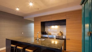 A modern kitchen with a central island, bar stools, and wooden cabinetry.