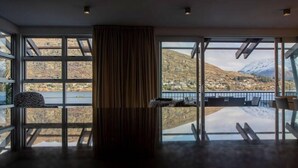 A modern room with large windows, a central pillar, and a view of a mountainous landscape.