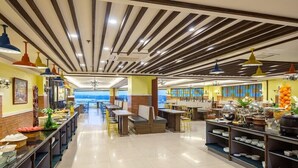 Een ruim restaurant met hoge plafonds, moderne hanglampen en diverse zitmogelijkheden, zoals tafels en ruimtes met banken.