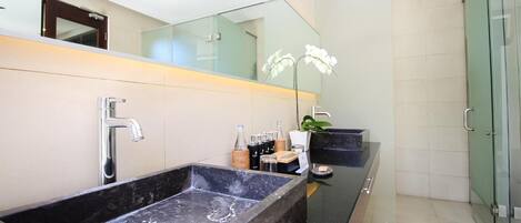 A modern bathroom with a large black sink, a glass shower enclosure, and a mirror above the sink.