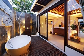 A modern bathroom with a freestanding bathtub, a glass-enclosed shower area, and a bed with a canopy. - Chandra Bali Villas (Seminyak)
