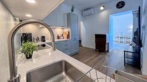 Una cocina moderna con un lavamanos de acero inoxidable, una cafetera y un comedor con mesa y sillas.