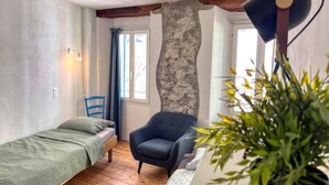 Una habitación pequeña y acogedora con cama, una silla y pared de piedra.