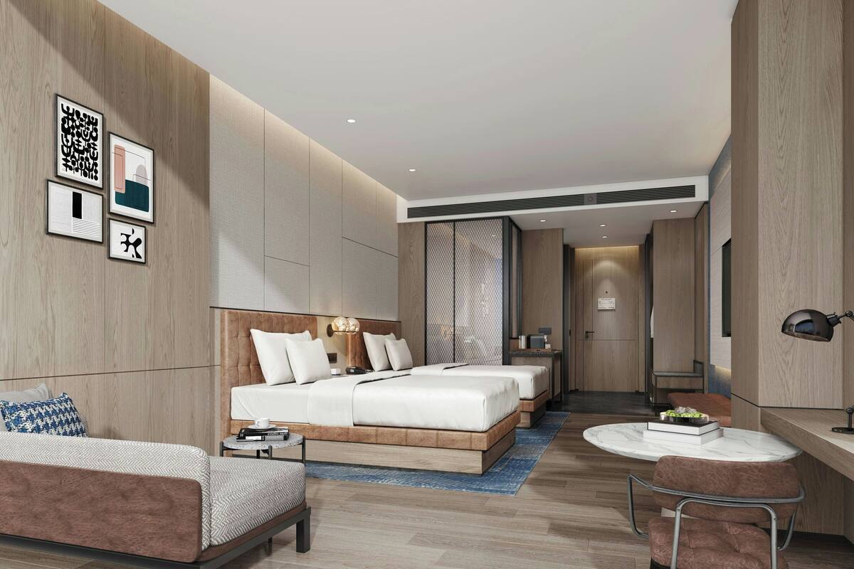 Una habitación de hotel moderna con una cama grande, una cama más pequeña, un sofá, un escritorio y una silla.