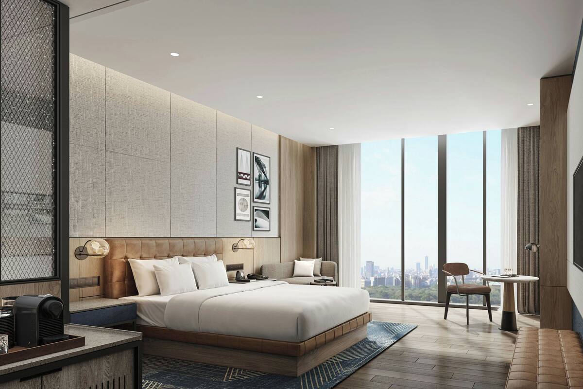 Habitación de hotel moderna con una cama grande, un escritorio y una silla. Se ve una vista de la ciudad a través de los amplios ventanales.