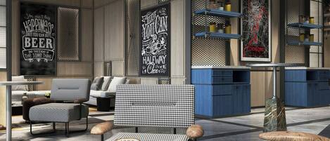 A modern interior with a seating area featuring a checkered sofa, a green chair, and a brown suitcase. There are shelves with decorative items and a wall with a poster.