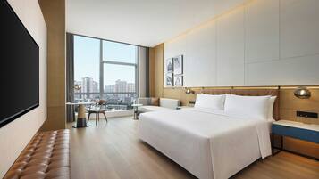 A modern hotel room with a large bed, a seating area with a view, and a television.