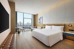 A modern hotel room with a large bed, a seating area with a view, and a television. - Four Points by Sheraton Chongqing Jiulongpo (Chongqing)